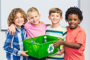 Portrait of kids holding recycled bottle in box