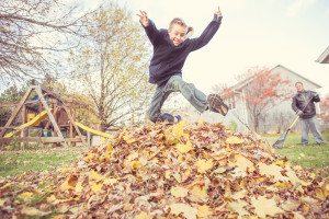 Boy taking a break from chores to jump in the leaves